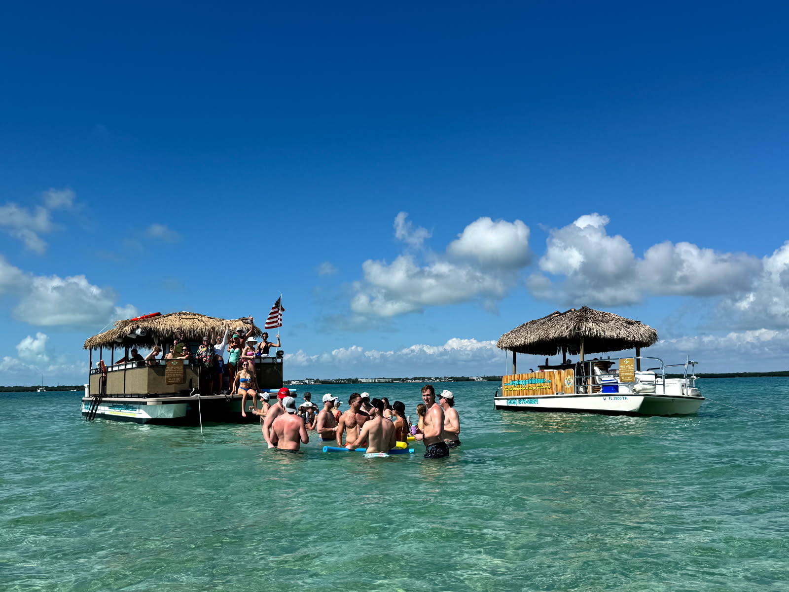 People enjoying the sea near a tiki boat during Coast Guard approved tiki boat tours in Key Largo