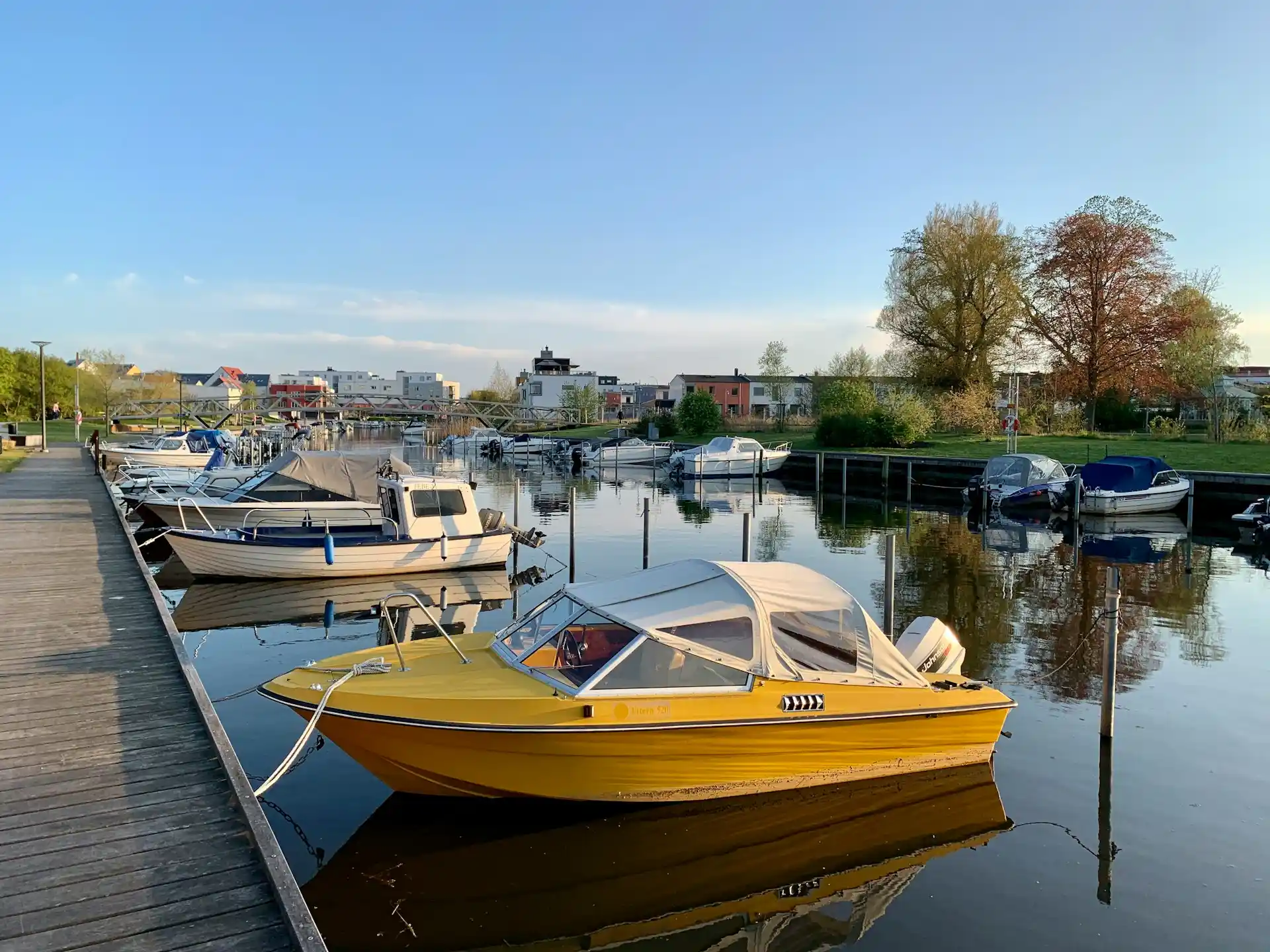 Various small boats, including a bright yellow one, docked in a calm marina under a clear sky, prompting thoughts on are boat rentals worth the money.