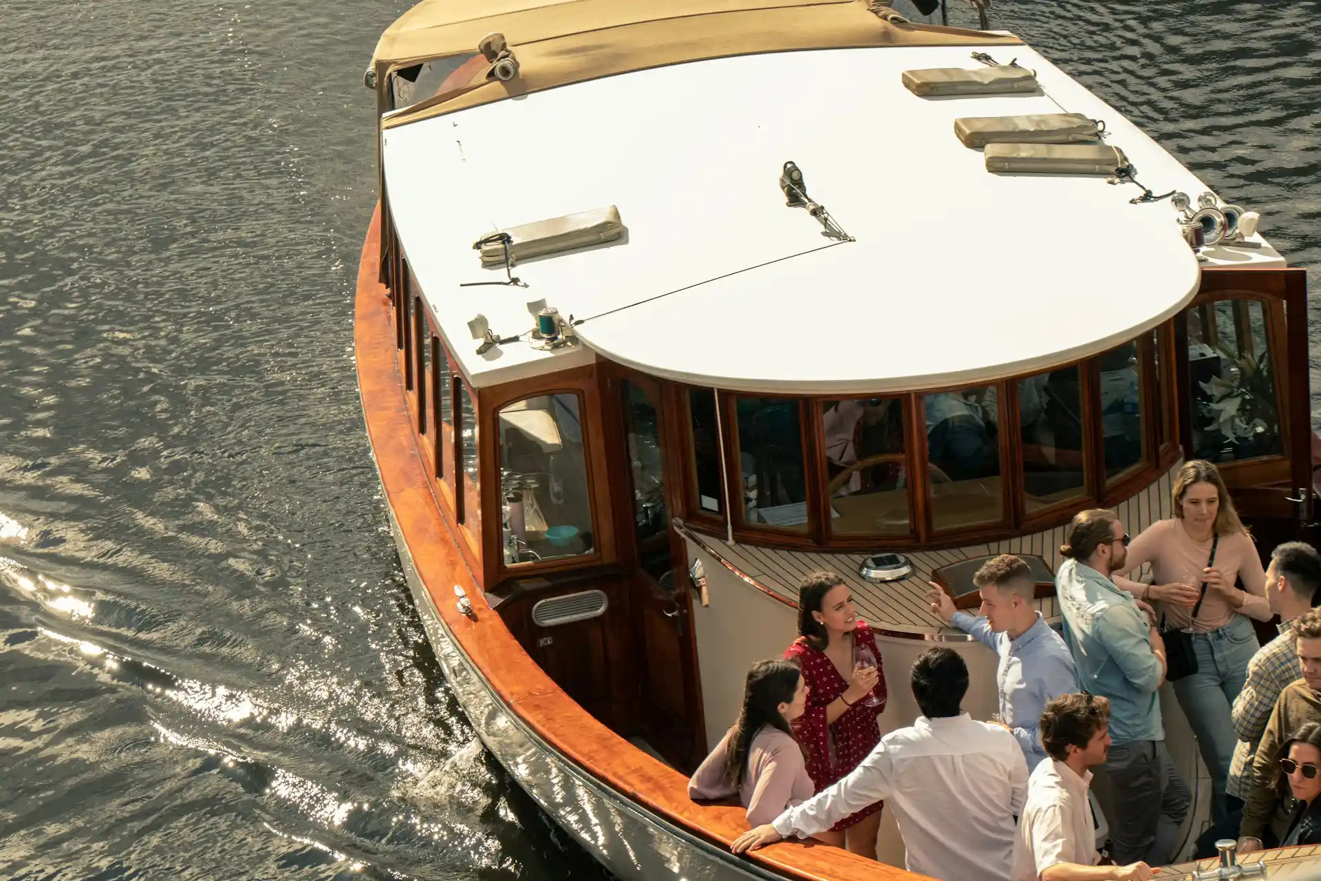 A group of people enjoying themselves on a wooden party boat moving on the water, making one wonder how much to rent a party boat.