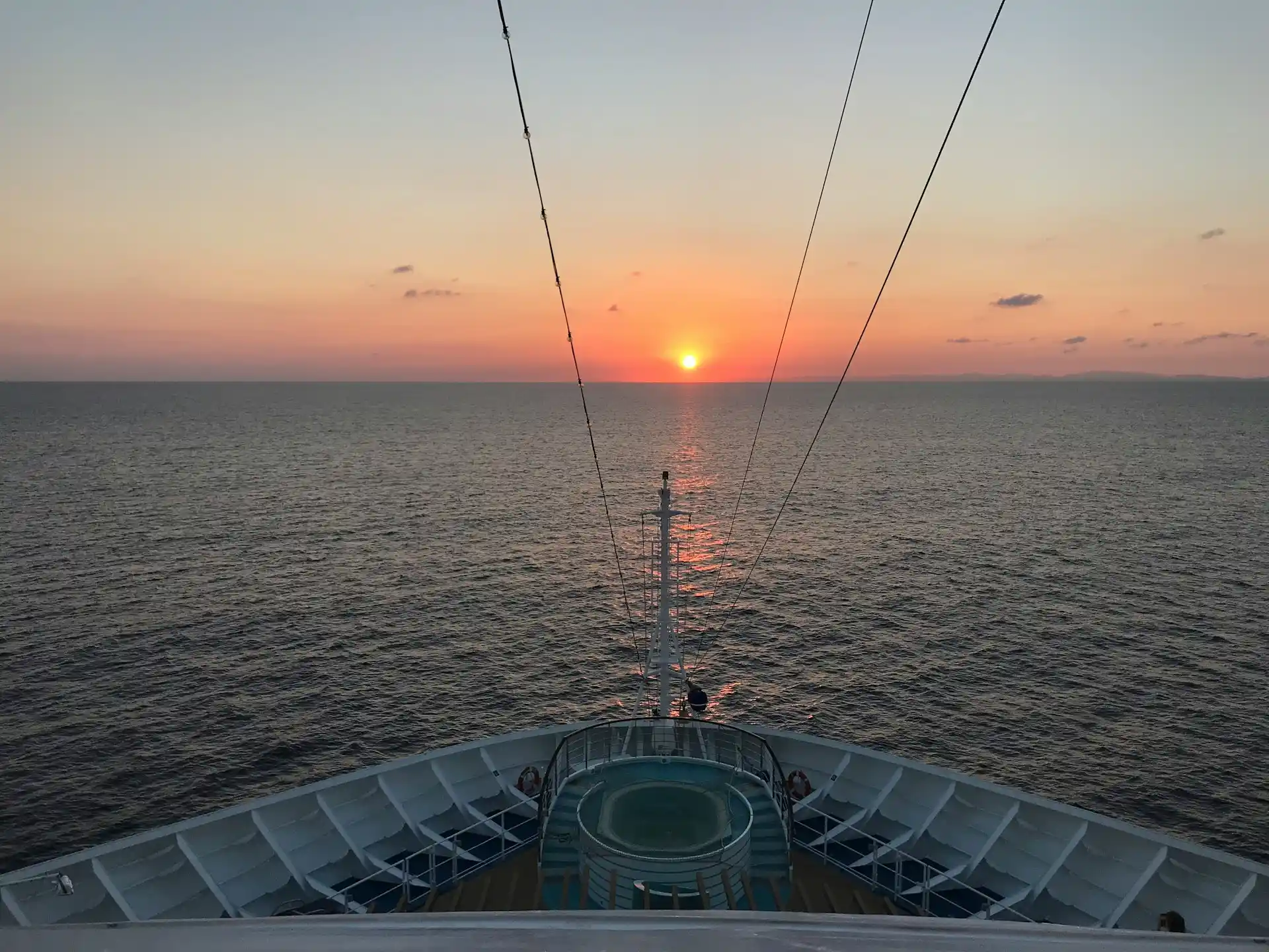 The bow of a cruise ship facing a vibrant sunset over the ocean, symbolizing the unforgettable moments and highlights often experienced on tours, like the Tiki Tours 2025 Highlights.