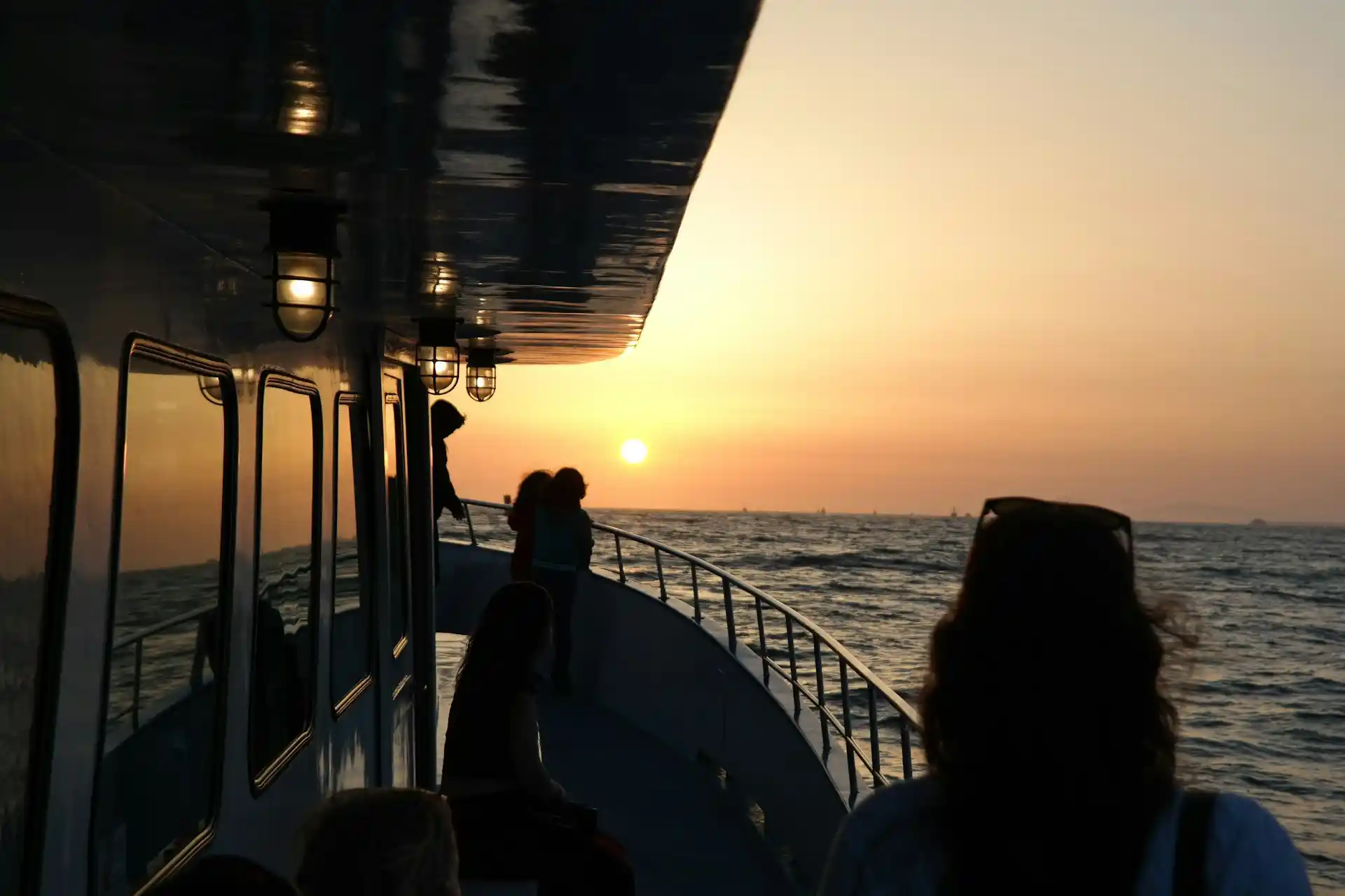 People on the deck of a boat watching a vibrant sunset over the ocean, capturing one of the Best Guest Moments of 2025.