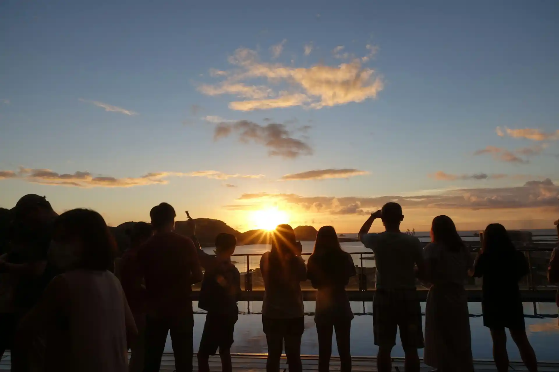 Silhouettes of people watching a vibrant sunset over the water, capturing a quintessential Instagrammable Tiki Tour Moments.