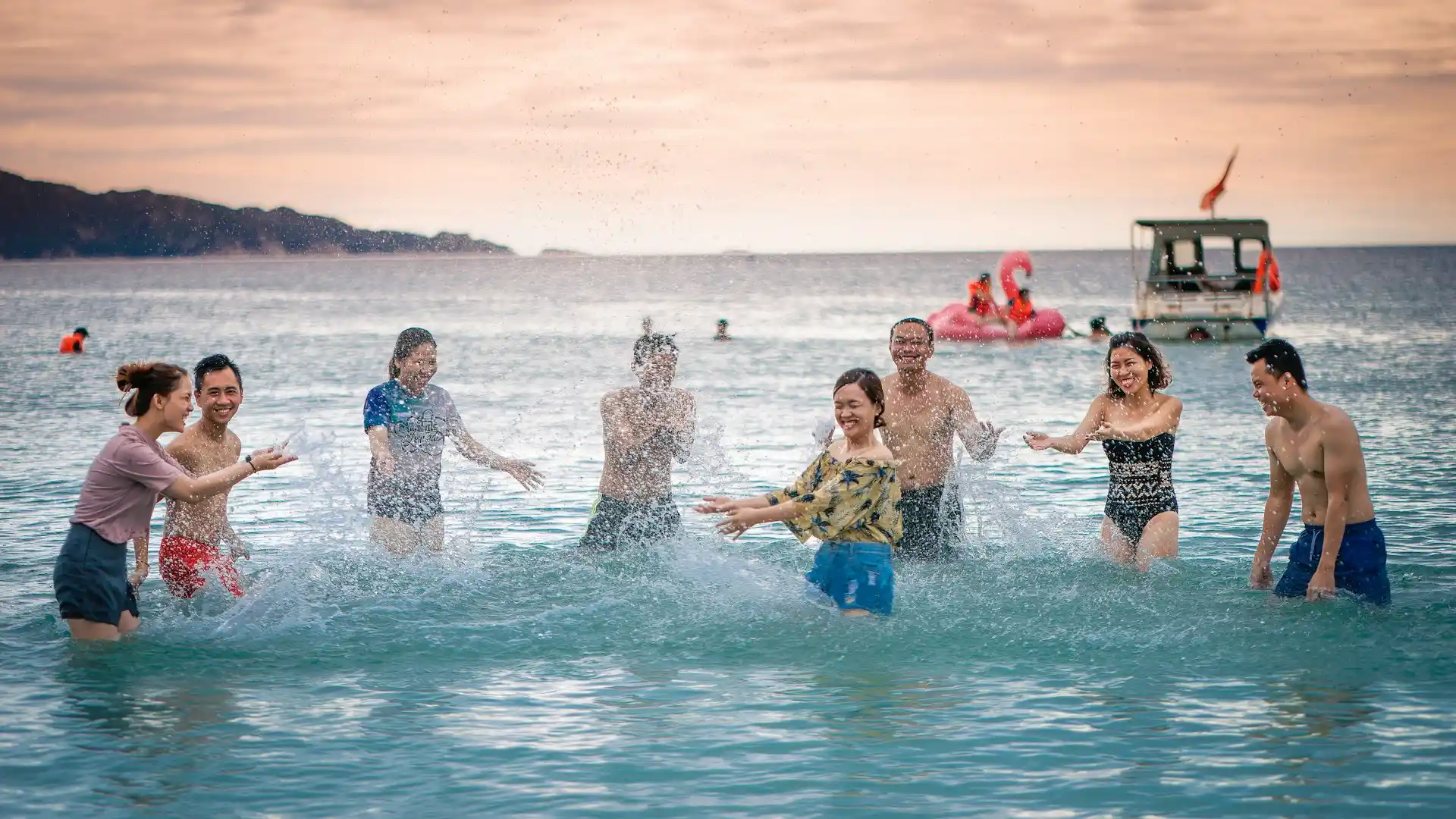 A group of joyful people splashing in the ocean at sunset, evoking the celebratory and memorable atmosphere perfect for Tiki Tour Proposals 2025.