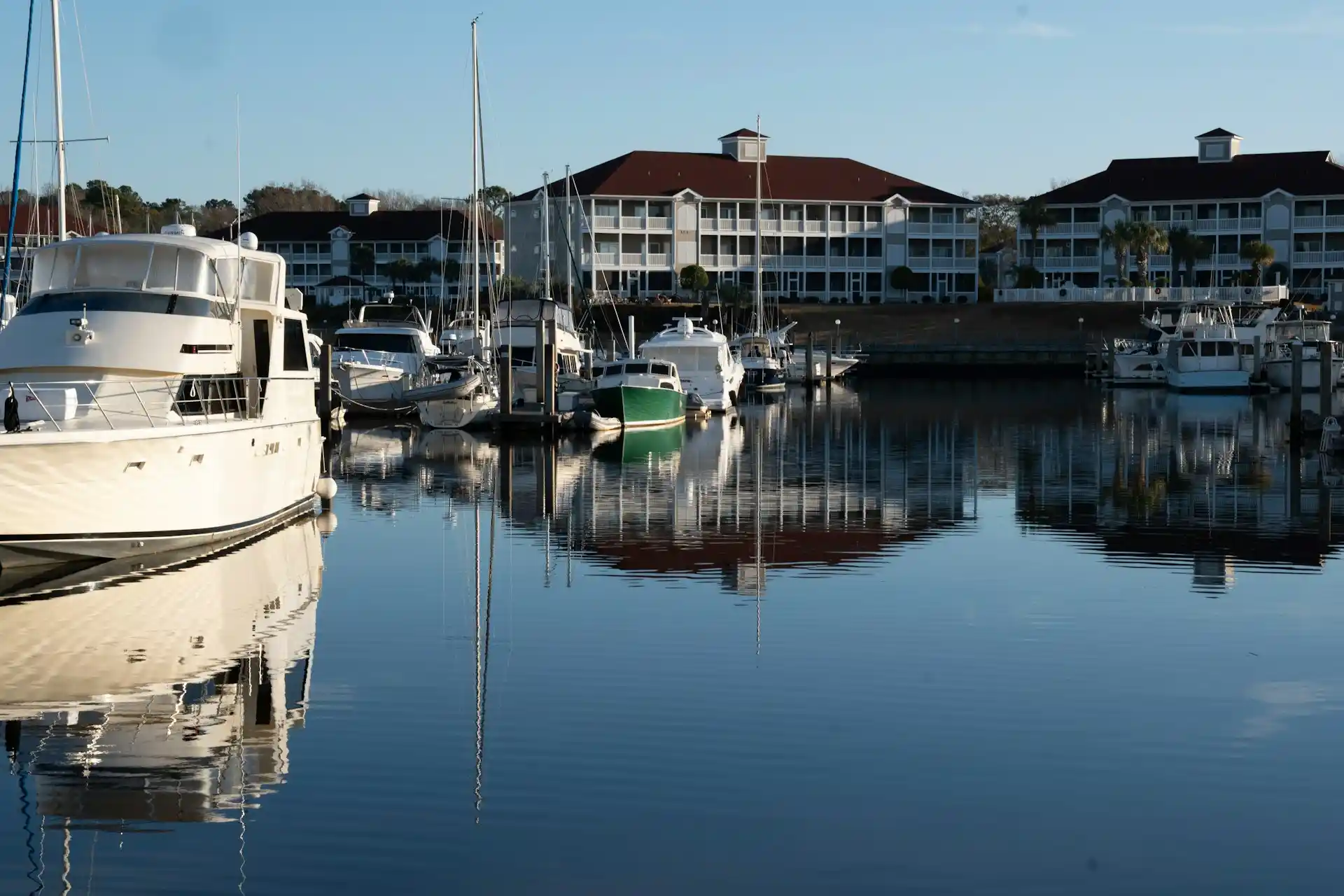 A tranquil marina scene with various boats docked, reflecting on calm water, prompting inquiry into How Do Boat Rentals Work?